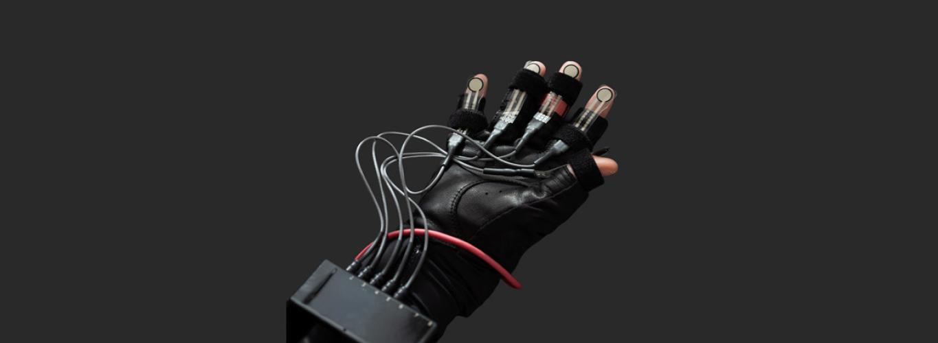 A human hand with its palm facing up, wearing a motion-sensor glove to generate and annotate robotics data.